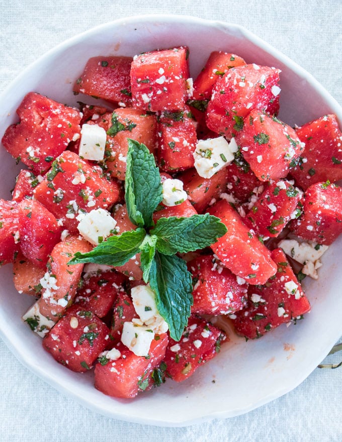 overhead of a bowl of watermelon and feta salad with a mint sprig