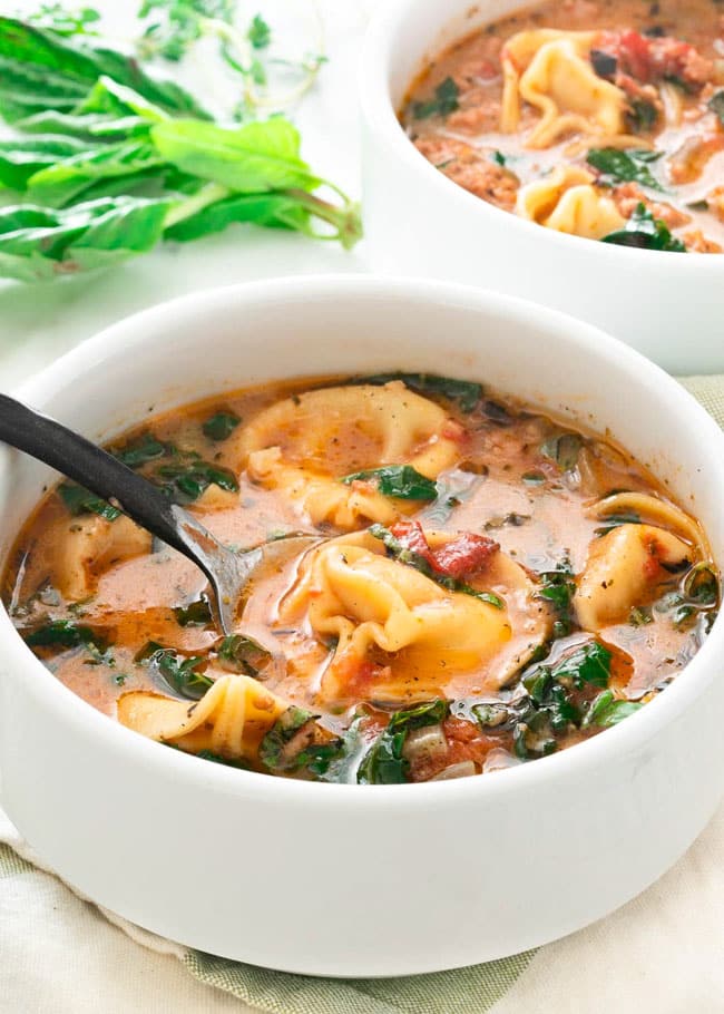 a bowl of tortellini soup with a spoon