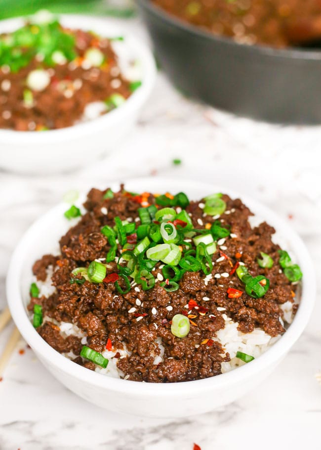 a Korean beef and rice bowl topped with green onion and sesame seeds