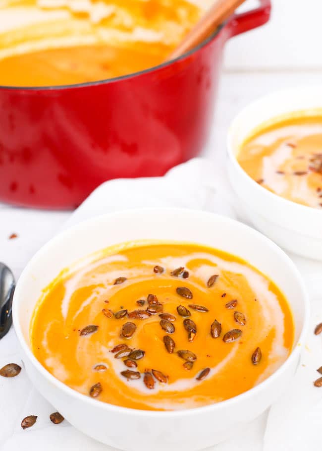 a bowl of butternut squash carrot soup topped with pepitas