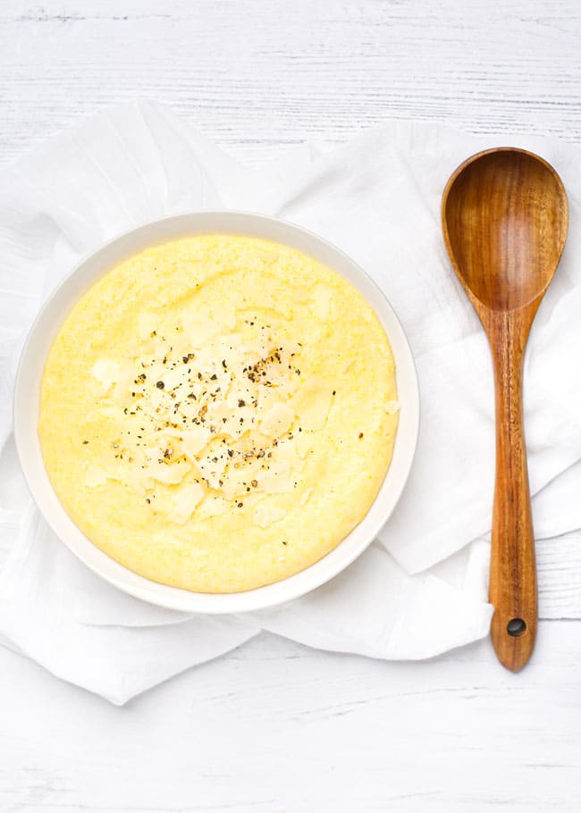 overhead shot of a bowl of creamy polenta topped with parmesan cheese and pepper