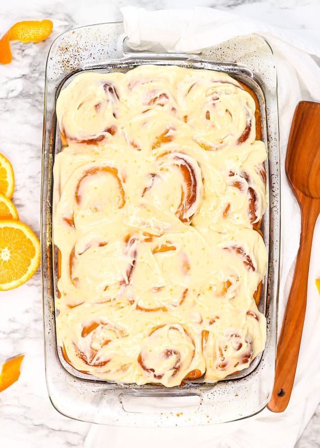 overhead photo of a baking dish filled with orange rolls topped with cream cheese icing
