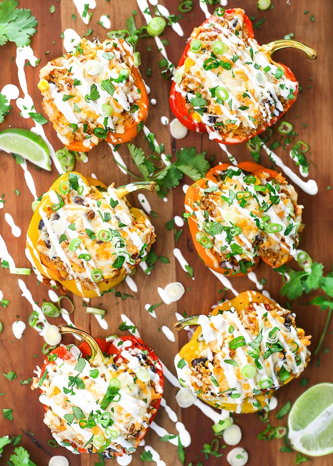 overhead photo of quinoa stuffed peppers drizzled with sour cream, green onion, and cilantro