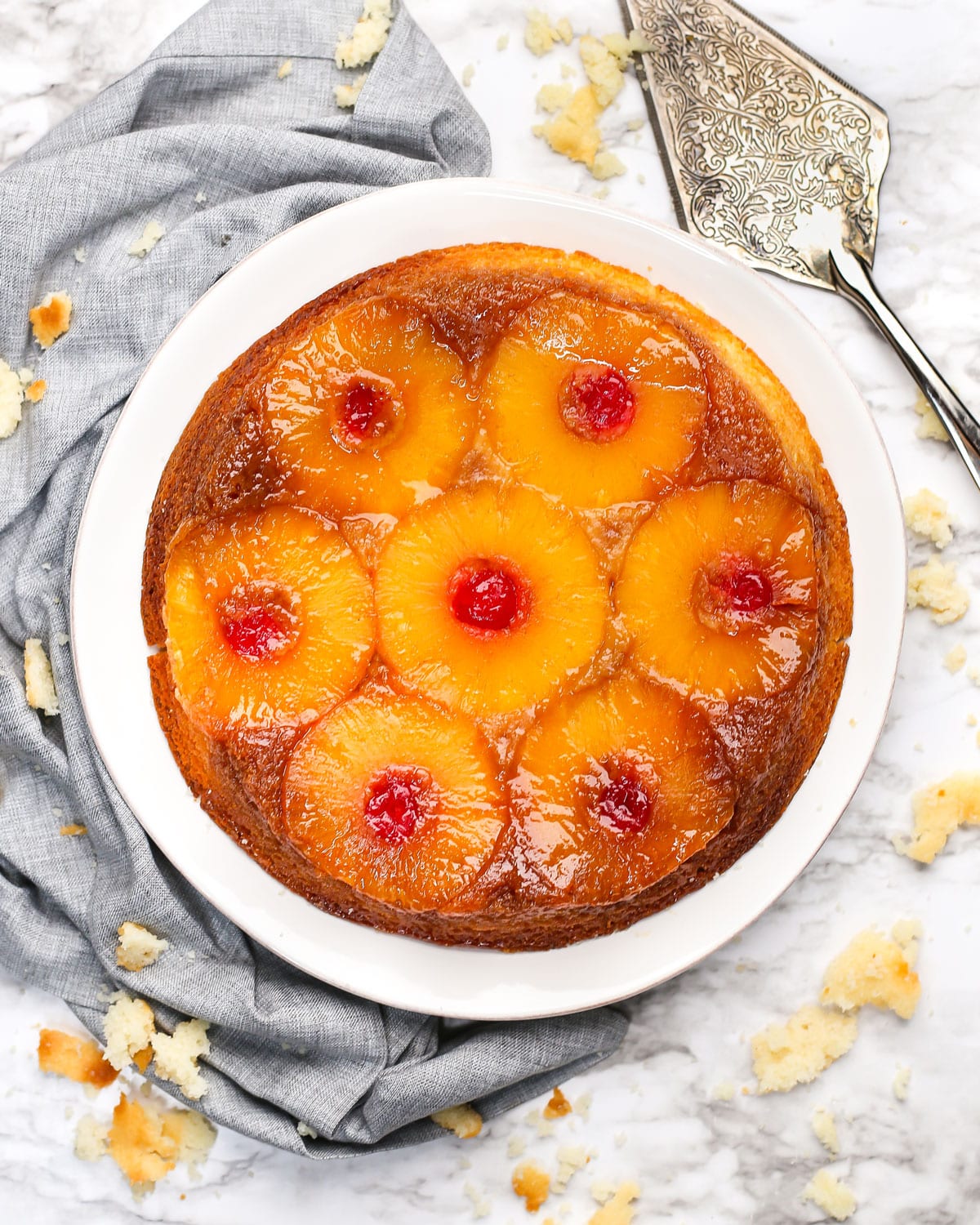 overhead photo of a pineapple upside down cake on a plate with a cake server