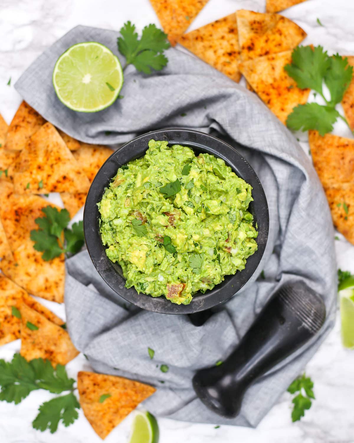 overhead photo of a mortar filled with guacamole surrounded with tortilla chips