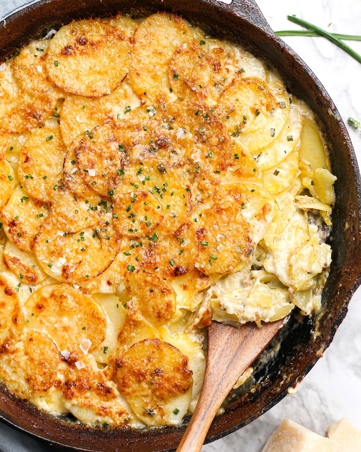 a skillet of au gratin potatoes with a spatula grabbing a scoop