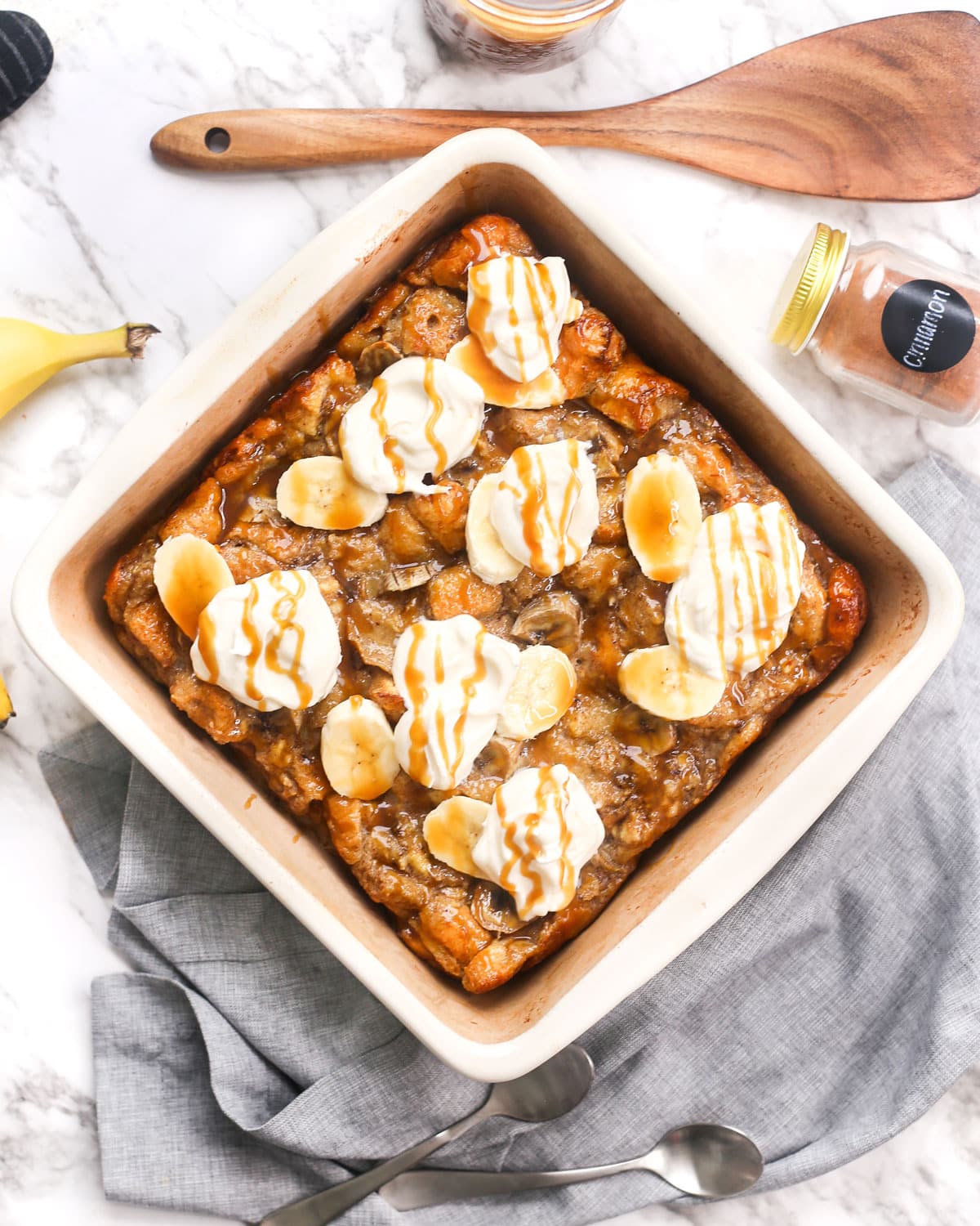 a baking dish of banana bread pudding topped with whipped cream and caramel