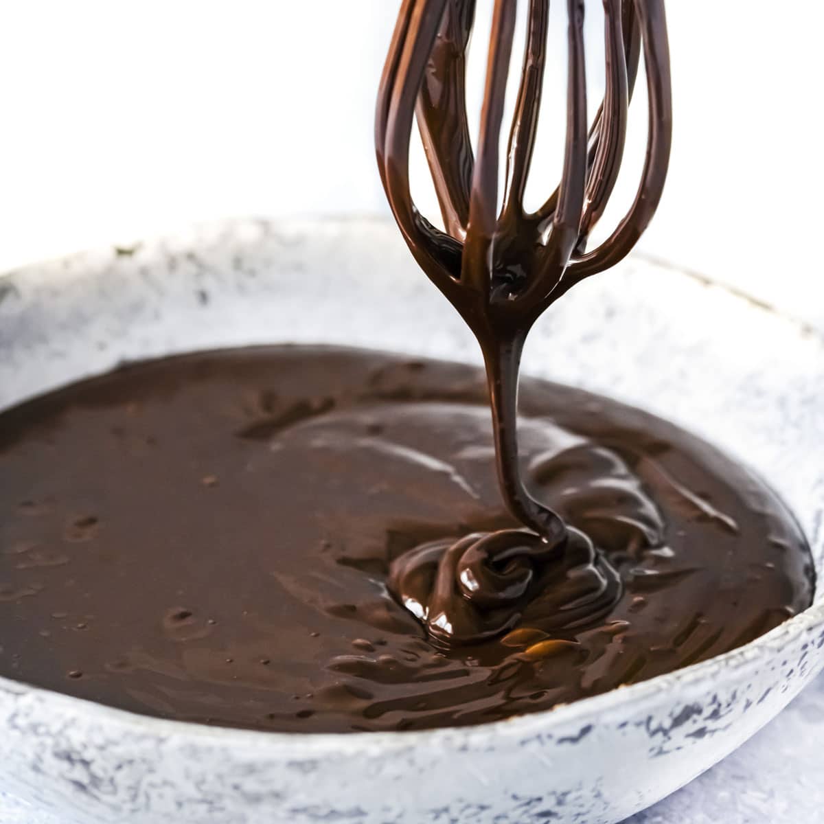 chocolate ganache dripping from a whisk