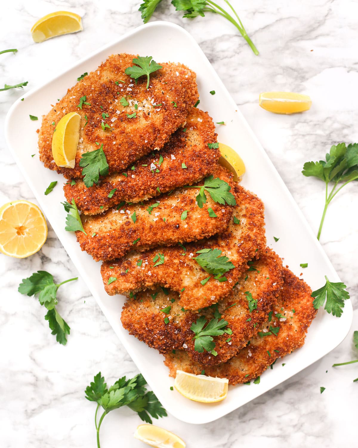 pork schnitzels on a platter with lemon wedges and parsley
