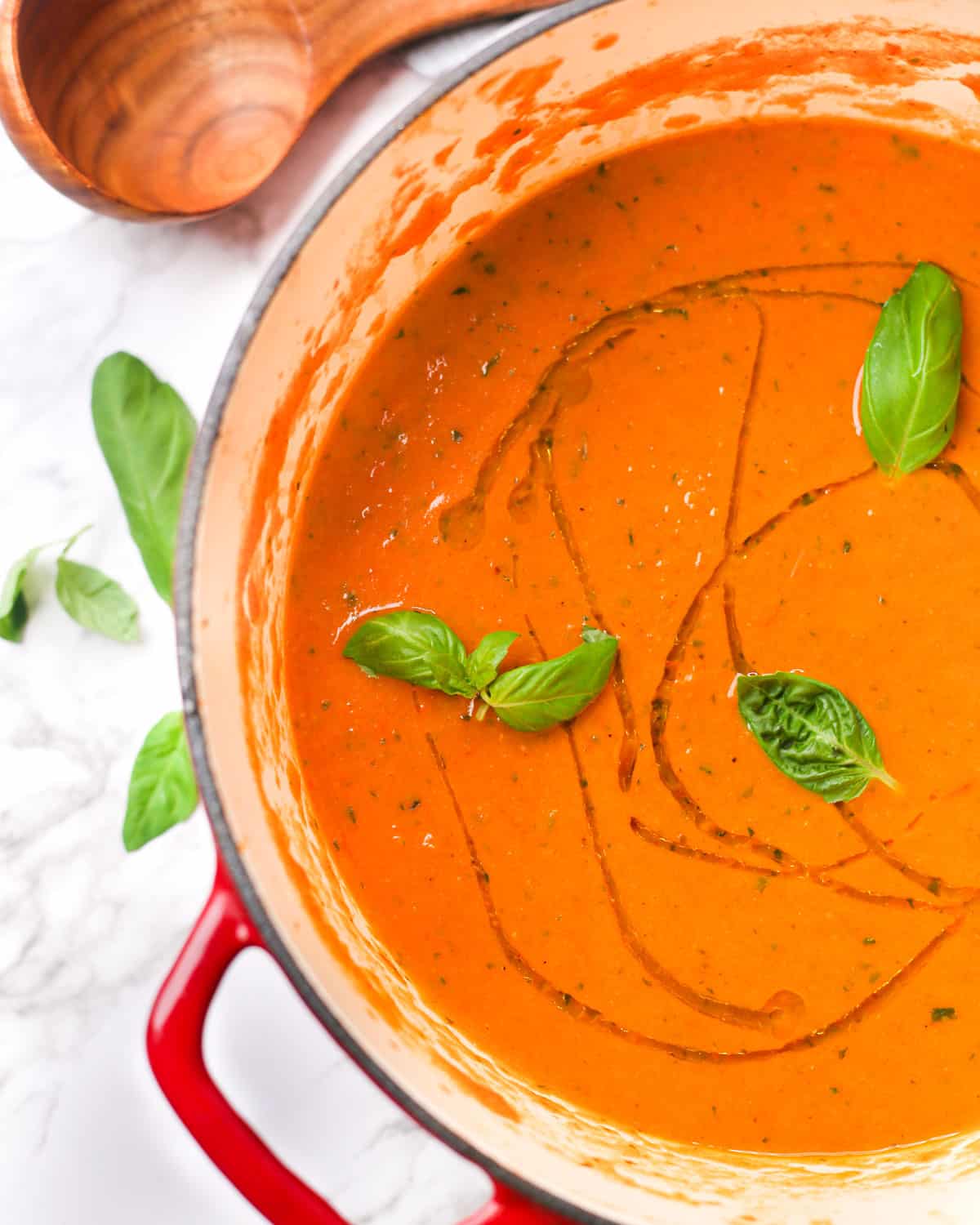 a pot of creamy roasted tomato soup topped with fresh basil