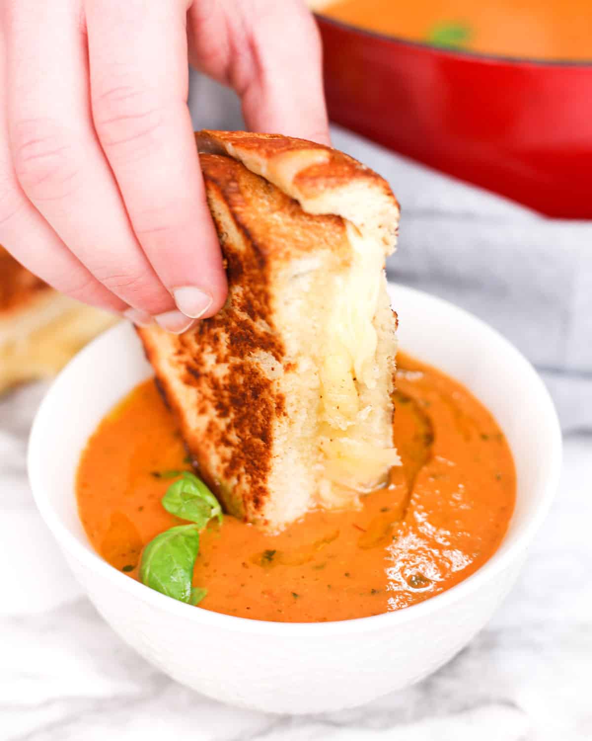 dipping a grilled cheese sandwich into roasted tomato soup