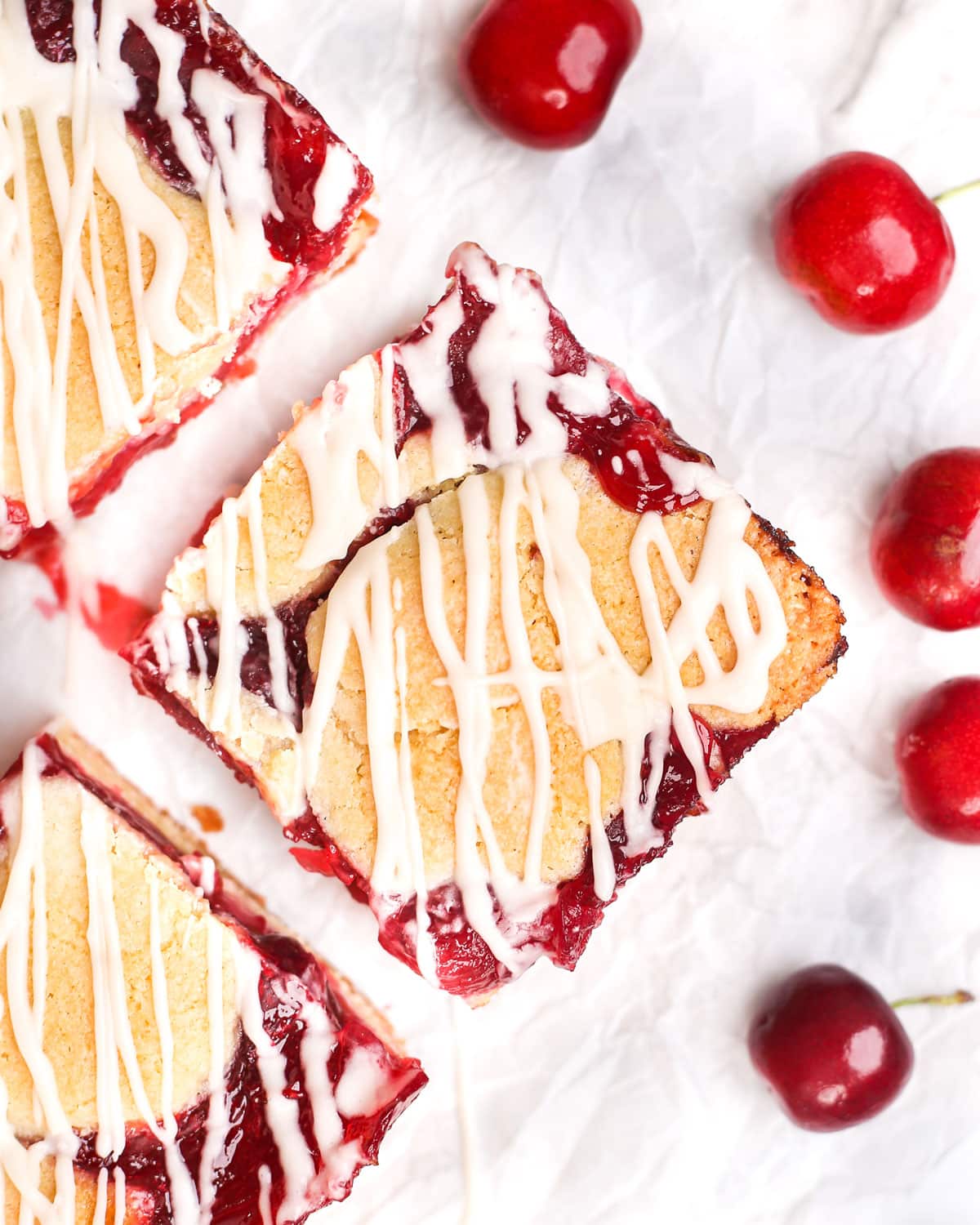 homemade cherry pie bar surrounded with fresh cherries and drizzled with glaze
