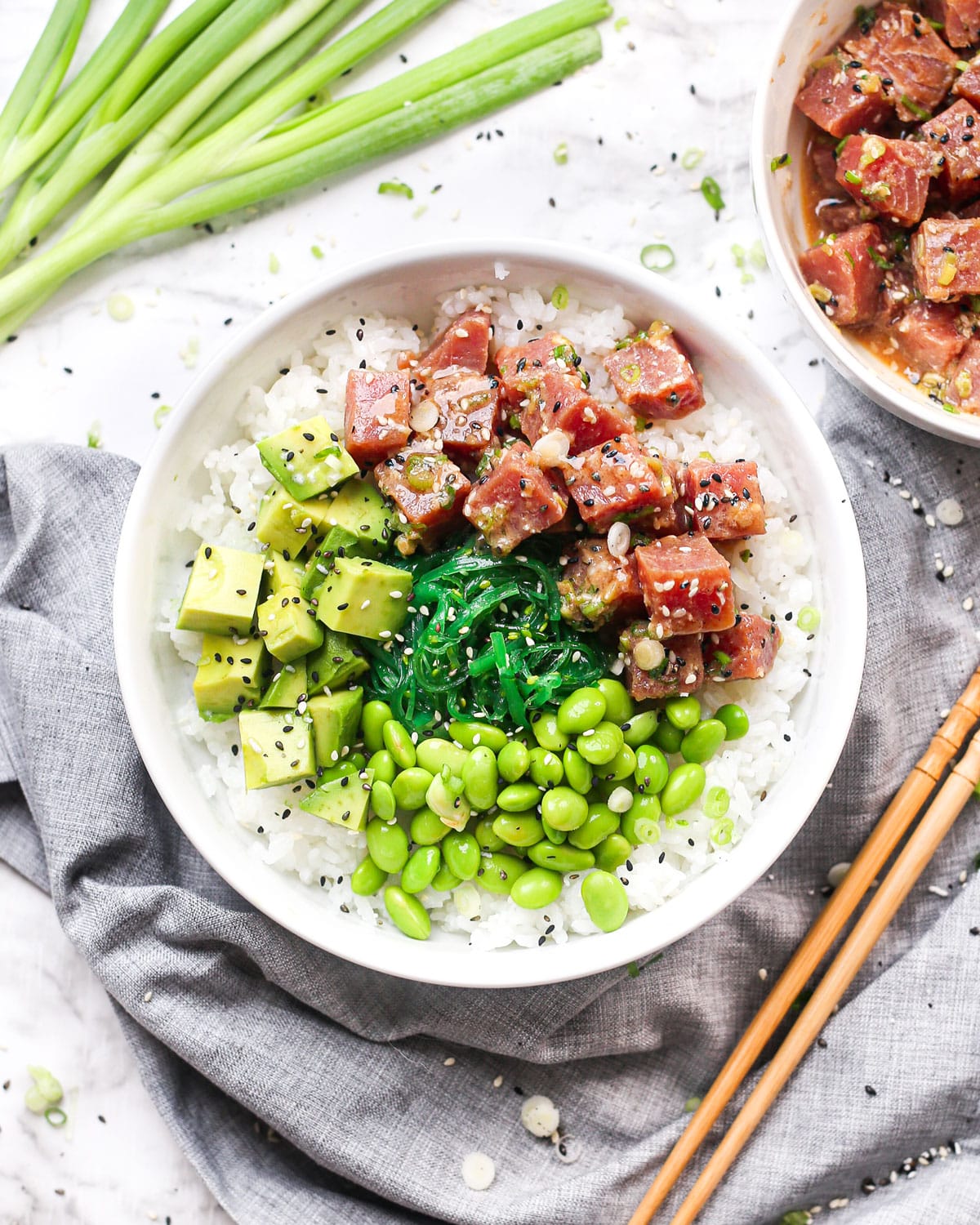 a tuna poke bowl topped with avocado, edamame beans, and seaweed salad