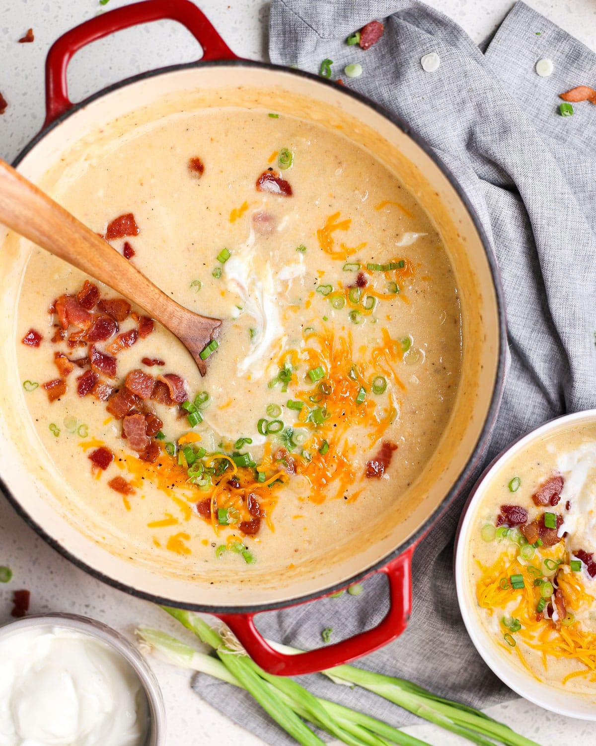 loaded baked potato soup in a large pot with a wooden ladle