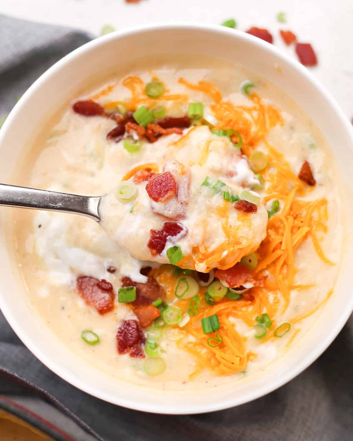 a spoon lifting a bite of loaded baked potato soup
