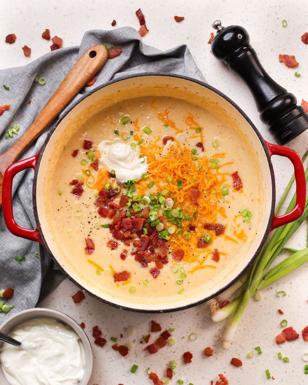 a large pot of loaded baked potato soup topped with sour cream, bacon, green onion, and cheddar cheese